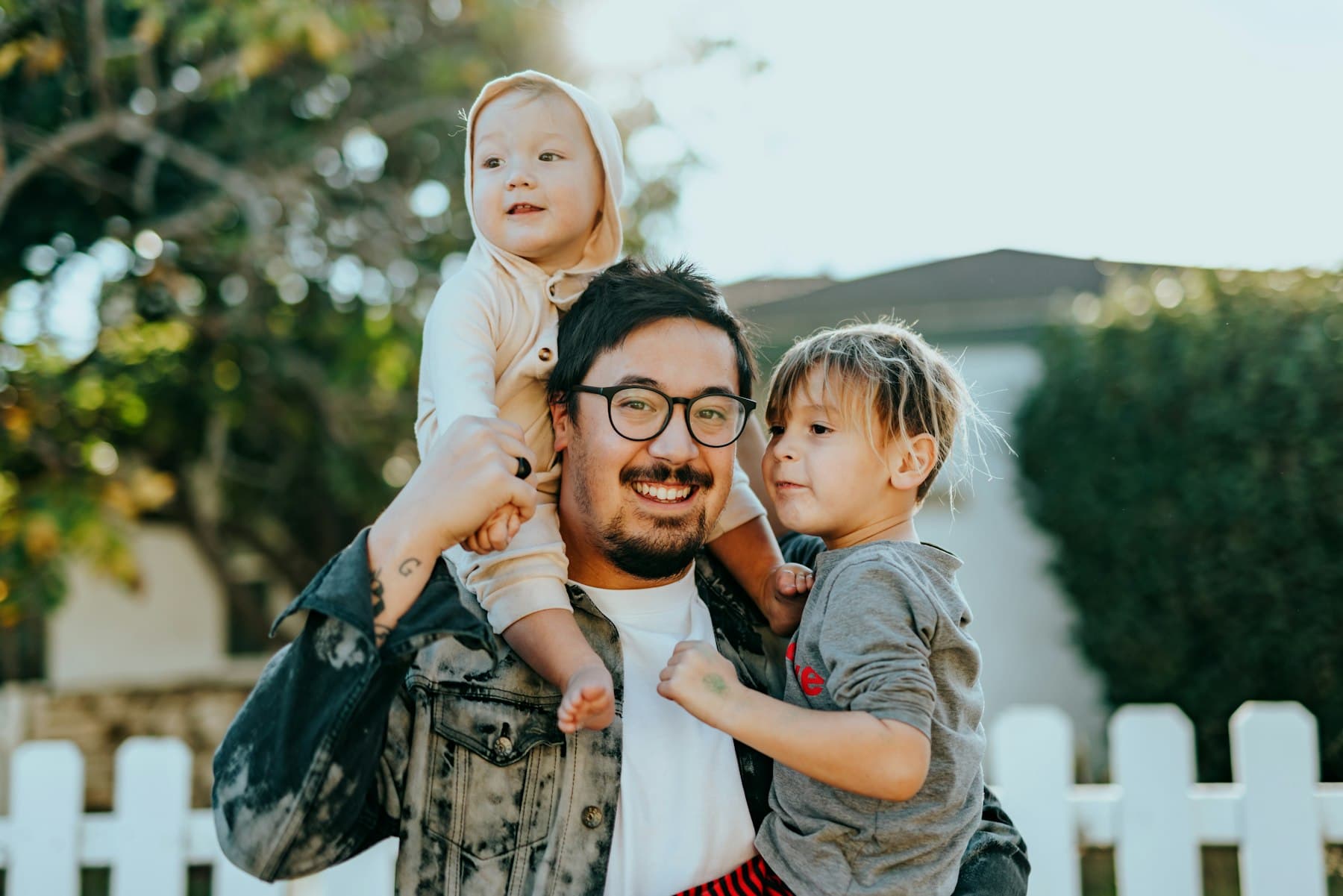 Dad holding his kids outdoors, smiling